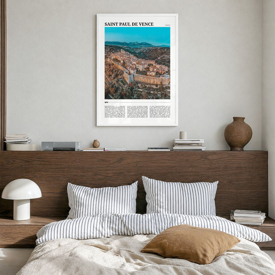 Saint-Paul-de-Vence Travel Poster in a white wood frame, hanging in a bedroom