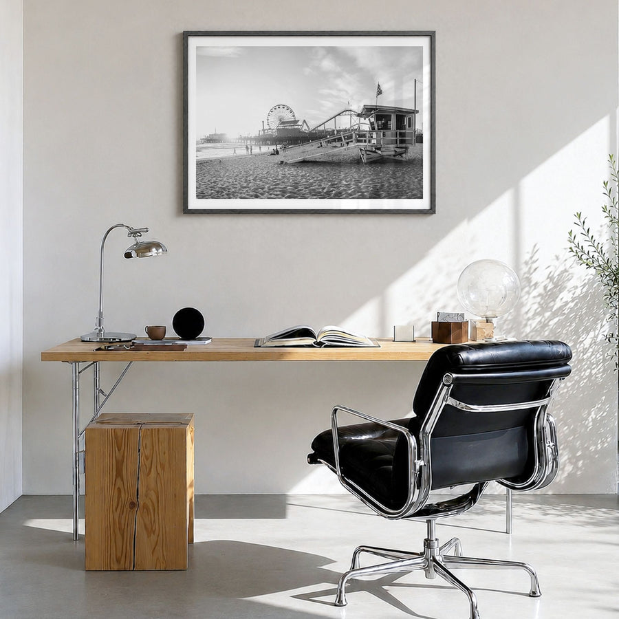 Santa Monica Photo Poster in a black wood frame, hanging in a bright home office, white border