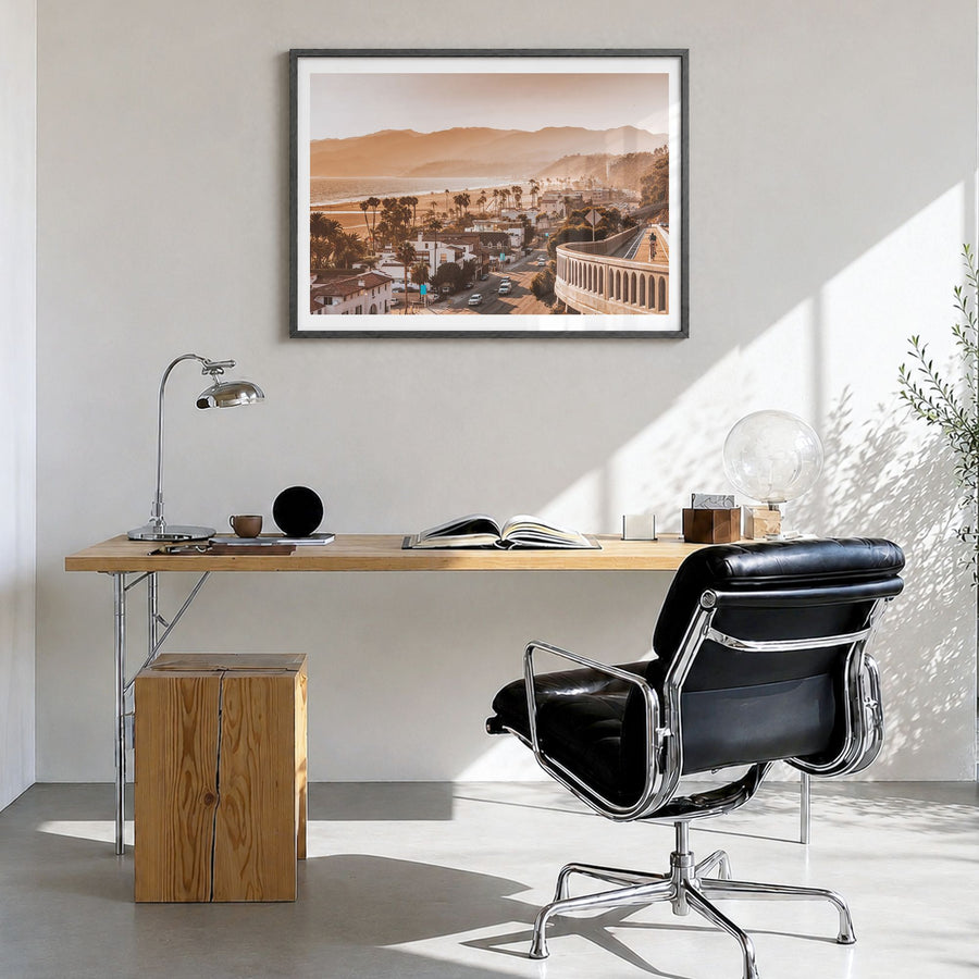 Santa Monica Photo Poster in a black wood frame, hanging in a bright home office, white border