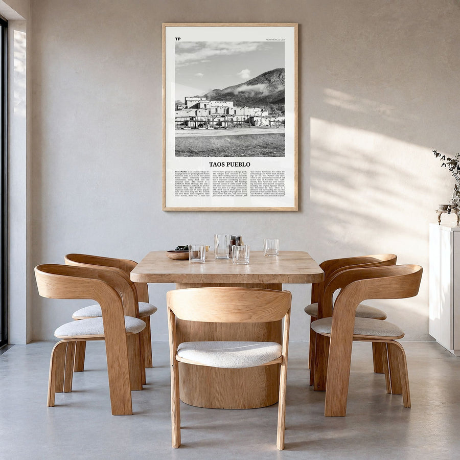 Taos Pueblo Newspaper Poster in a natural wood frame, hanging in a dining room