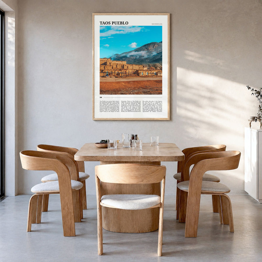 Taos Pueblo Travel Poster in a natural wood frame, hanging in a dining room