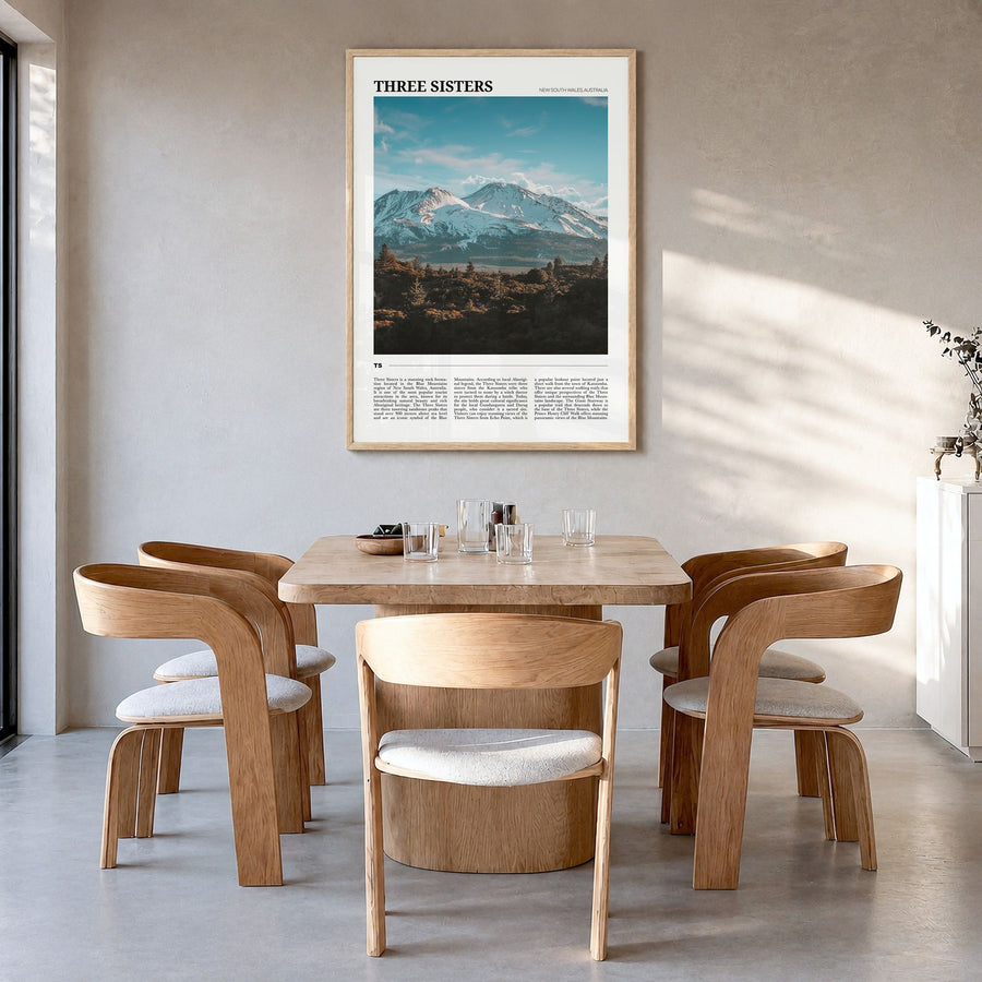 Three Sisters Travel Poster in a natural wood frame, hanging in a dining room