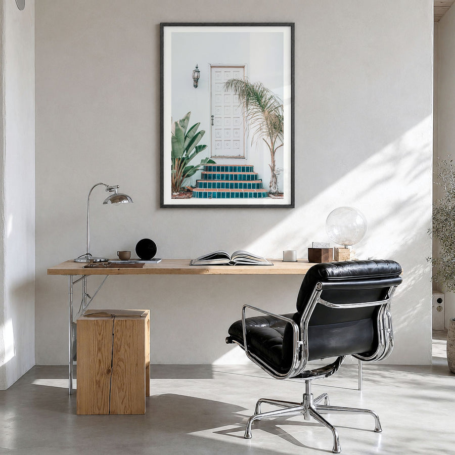 White Door Photo Poster in a black wood frame, hanging in a bright home office, white border